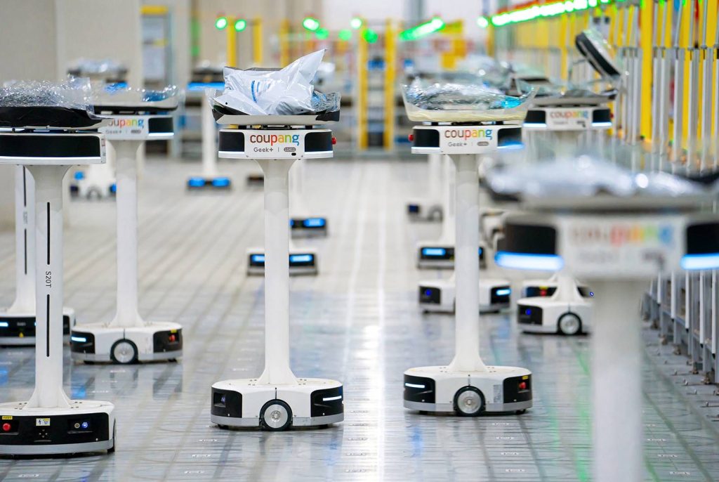 酷澎物流中心的揀貨機器人，靠掃描地板上的QR Code移動，快速把商品放到各營業所的物流箱中。